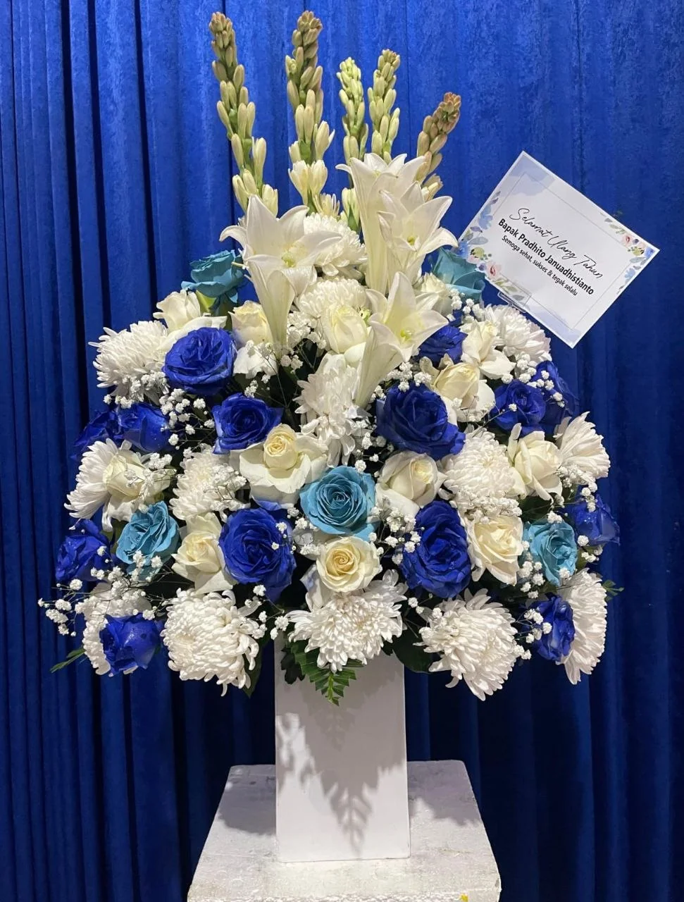 Bunga meja biru putih dalam vas tinggi